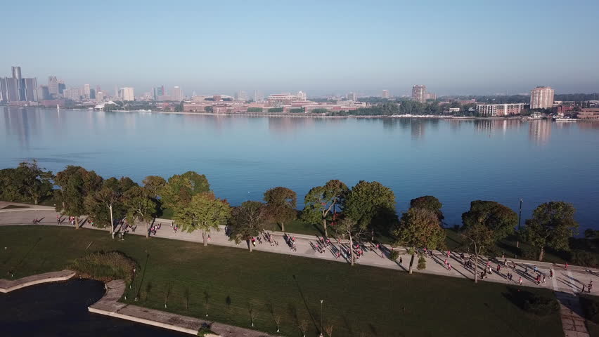 View of the Detroit skyline from Belle Isle on the Detroit river. Lake freighter passing by on a sunny summer day with blue sky. Aerial drone video of Michigan.