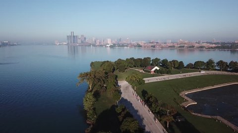 View of the Detroit skyline from Belle Isle on the Detroit river. Lake freighter passing by on a sunny summer day with blue sky. Aerial drone video of Michigan.