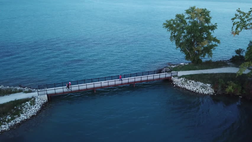 Belle Isle Detroit aerial view at sunset on a summer day. Bridge and buildings visible in the distance. Island silhouette on the Detroit river with the Detroit skyline in the background.