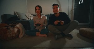 Slow motion of an young couple having fun to play a video games in living room in the evening.