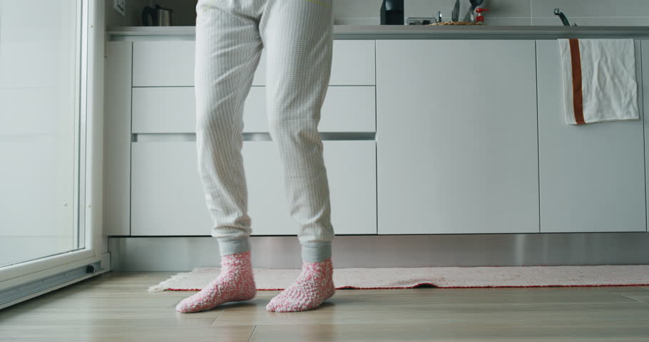 Slow motion  close up of  young woman in pajamas is listening to the music and dancing after morning coffee in the kitchen.