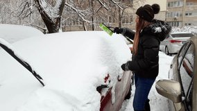 4k video of smiling young woman cleaning her car from snow before riding to work