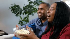 Young couple at home eating popcorn and watching a movie