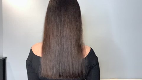 Brunette woman waving her beautiful, healthy hair after a treatment in a beauty salon.Slow motion