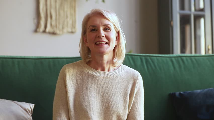 Smiling middle aged mature woman waving hand looking at camera sit on couch, older senior lady making video call on dating online talking to webcam at home, elderly people online communication Royalty-Free Stock Footage #1029041519