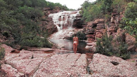Aerial: Beautiful Sexy Young Woman in front of Scenic Waterfall in Chapada, Brazil