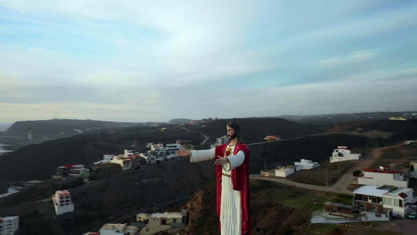 Aerial Pan Right: Large Jesus Statue Overlooking Town In Large Valley By Sea in Baja Malibu, Mexico
