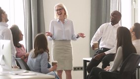 Mature female business coach leader talk to multiracial team business people laugh together at corporate training, diverse employees group and mentor have fun at meeting involved in funny discussion - Powered by Shutterstock - Get 15% off with code: PIKWIZARD15