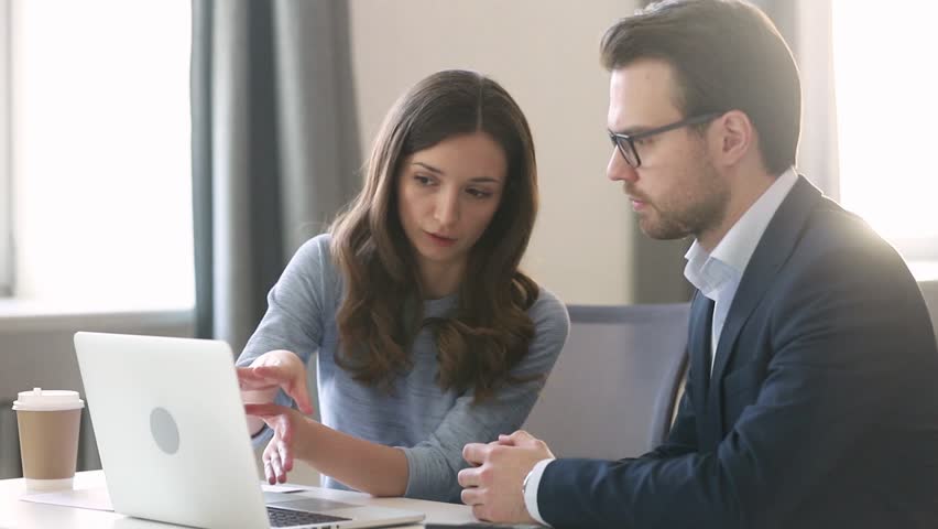 Female manager insurer consulting male customer with laptop at meeting, young saleswoman or mentor showing online presentation of deal benefits talking convincing client teaching intern sit at desk | Shutterstock HD Video #1029051425