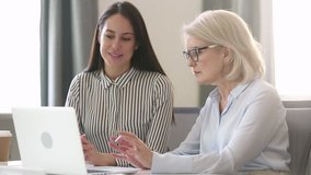 Older female professional mentor teach young intern worker learn new skill look at laptop, mature businesswoman executive manager explain colleague computer work talk consult client with computer - Powered by Shutterstock - Get 15% off with code: PIKWIZARD15