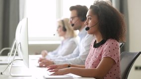 Serious african female call center agent wear wireless headset using computer looking at screen consulting customer with online problem, focused black woman operator working in support service office