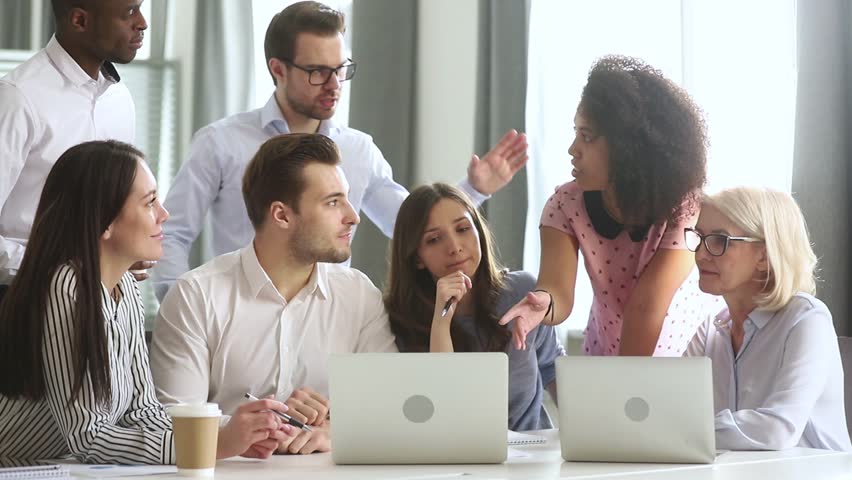 Diverse office workers team gather talking discussing online project laugh working together at corporate group business meeting, multiracial employees involved in teamwork in workplace with laptops Royalty-Free Stock Footage #1029051473