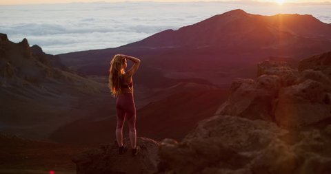 Young athletic woman enjoying an epic sunrise at the top of a mountain, breathtaking outdoor fitness model in slow motion