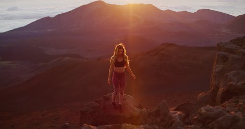 Young athletic woman hiking on the top of a mountain at sunrise, epic outdoor fitness in slow motion
