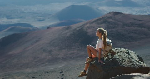 Young adventurous woman sitting and enjoying the view of amazing mountain landscape in solitude, amazing summer adventures
