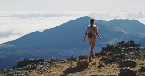 Young adventurous woman walking on the top of a mountain and enjoying an amazing view, epic summer adventure