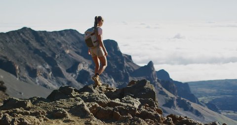 Young adventurous woman walking on the edge of a cliff and enjoying an amazing view, epic summer adventure