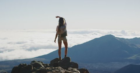 Young adventurous woman standing on the top of a mountain enjoying the view, active summer hiking lifestyle