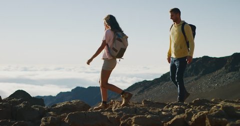 Young adventurous couple hiking together on the top of a mountain in slow motion, summer wilderness excursions