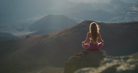 Young peaceful woman meditating on the top of a mountain, zen yoga meditation practice in nature