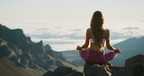 Young athletic woman meditating on the top of a mountain, zen yoga meditation practice in nature