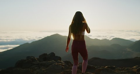 Young athletic woman walking to the top of a mountain to watch the sun rise, epic outdoors fitness in slow motion