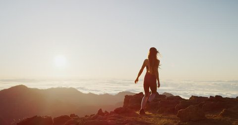 Young athletic woman running to the top of a mountain to watch the sun rise, epic outdoors fitness in slow motion
