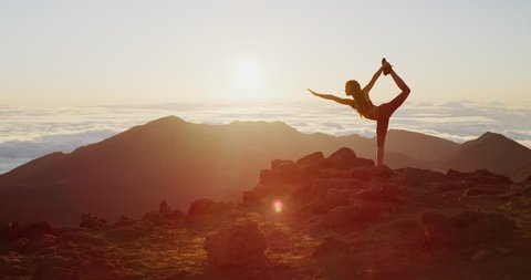 Young athletic woman performing yoga pose on the top of a mountain at sunrise, zen wellness woman performs dancer's pose