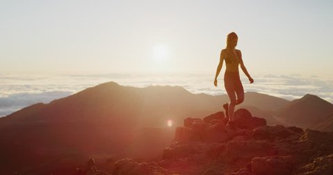Young athletic woman exploring the top of a mountain at sunrise in slow motion, epic outdoors fitness
