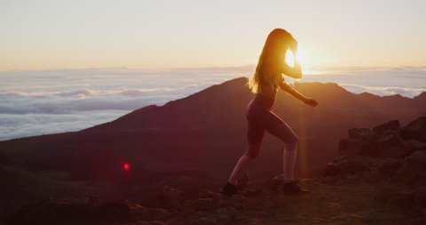 Young athletic woman jogging on the top of a mountain and watching the sun rise, epic outdoor fitness woman in slow motion