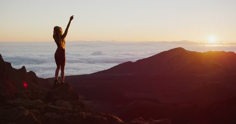 Young athletic woman enjoying an epic sunrise view from the top of a mountain, amazing outdoor fitness adventure