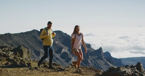 Young adventurous couple hiking together on the top of a mountain in slow motion, summer wilderness excursions