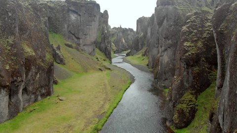 Aerial Forward: Small River Surrounded By Tall, Jagged Rocks On Either Side in Fjaorargljufur, Iceland