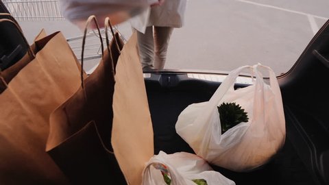 View from car: Woman puts shopping bags in the trunk of a car.