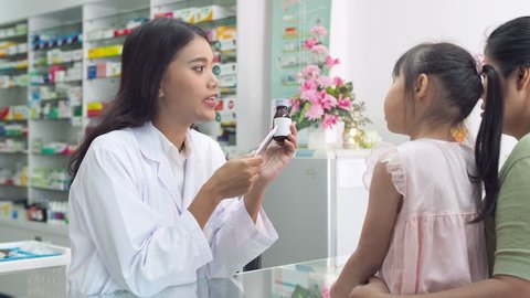 Beautiful asian Pharmacist explaining the medication to patient in drug store Stockvideó
