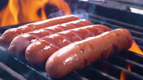 Barbecue Grill Cooking Healthy Low Fat Lean Meat Classic Takeaway Sausages Meal. Slow motion of hot dogs being cooked on an outdoor grill, being turned using a tongs. Making a picnic. Close up