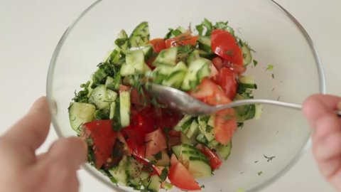 Preparation of tomato and cucumber salad. Cutting and mixing of ingredients.