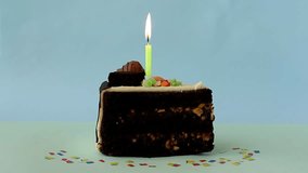 Piece of birthday chocolate cake with burning candle on blue background, Time lapse video. Happy Birthday!