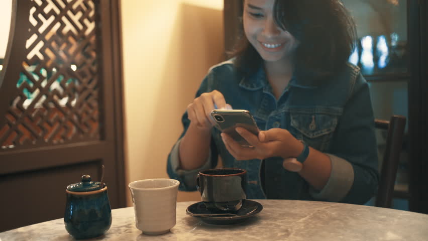Asian woman using mobile phone and drink coffee in the cafe