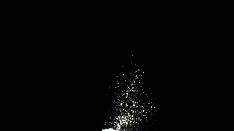 Close-up view of white flakes of powder flying on the black background. Stock footage. Contrast of white and black