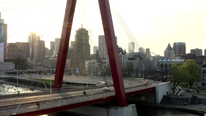 Willelmsburg in Rotterdam filmed by drone. Aerial shot of the red Willelmsburg in Rotterdam, Netherlands. The drone rises up the architecture of the bridge crossing the Maas. The sun is setting beauti