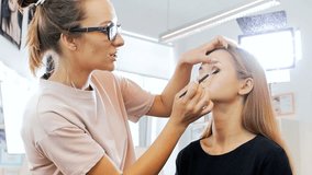 Closeup slow motion video of professional makeup artist applying makeup on models face before fashion show