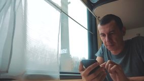 man travel writes smartphone a message social media in the messenger sits on the train by the window traveler concept train railroad journey travel. slow motion video. 