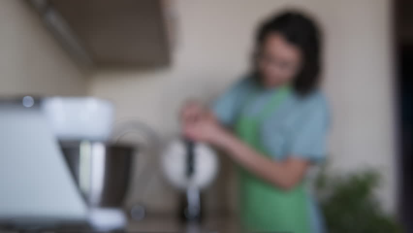 A woman in the kitchen brewing tea.