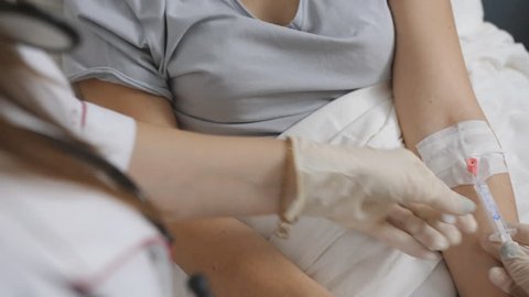 Nurse putting a drip into the catheter lying patients close-up