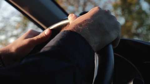 Male hands on the steering wheel of a car. Travelling by car. The businessman is holding the steering wheel. Family car trip. The driver is a businessman. Car driving concept. Family travel. 