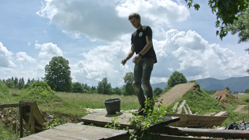 An athletic boy doing a backflip into fomepit in nature