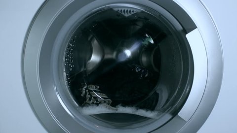 Washing things in the washing machine. The rotation of the drum of the washing machine close-up.