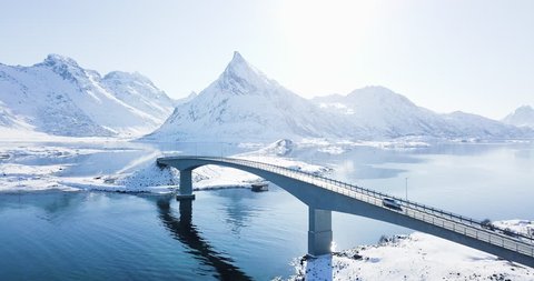 Scenic aerial footage of beautiful arctic Lofoten Islands winter wonderland scenery with car passing bridge on a sunny cold day, Fredvang, Lofoten archipelago, Norway, Scandinavia, northern Europe