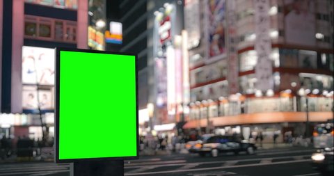 Modern billboard with a green screen, on the blurred megapolis background, neon street lights at night, traffic, Tokyo, Japan